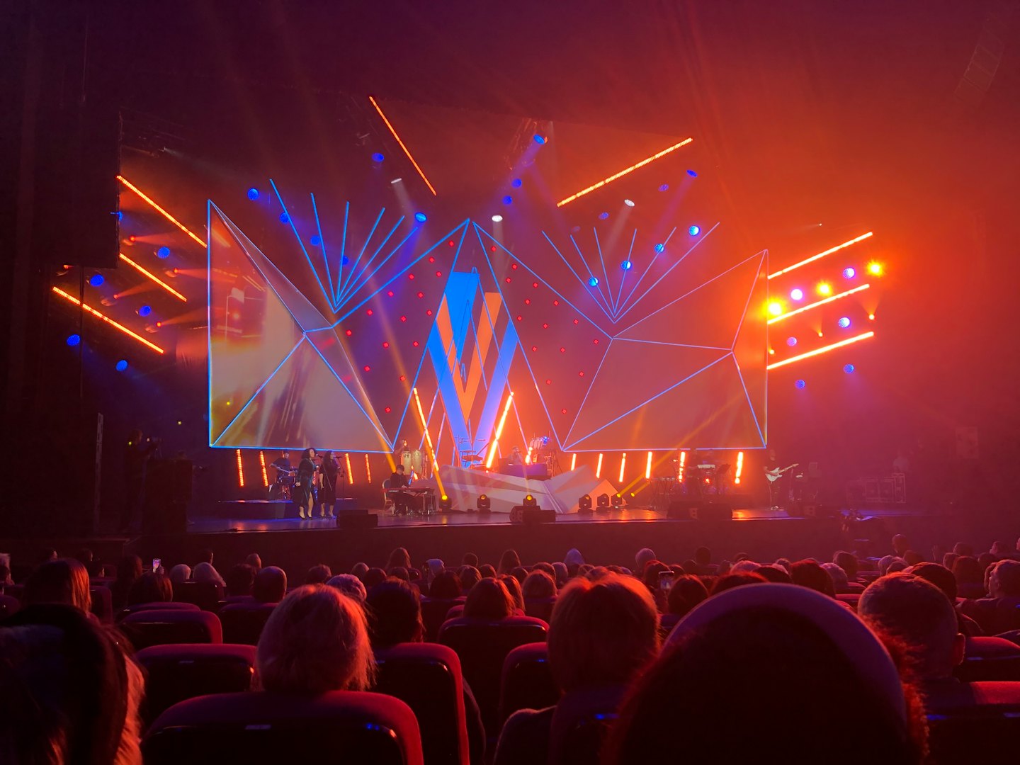 Il pubblico guarda i musicisti su un palco illuminato.